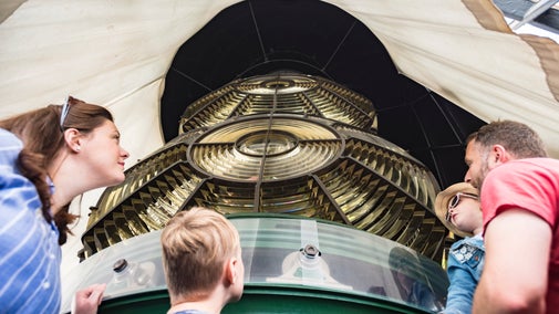 Two adults and two children look up at the huge, multi-faceted glass optic of Souter Lighthouse's lantern